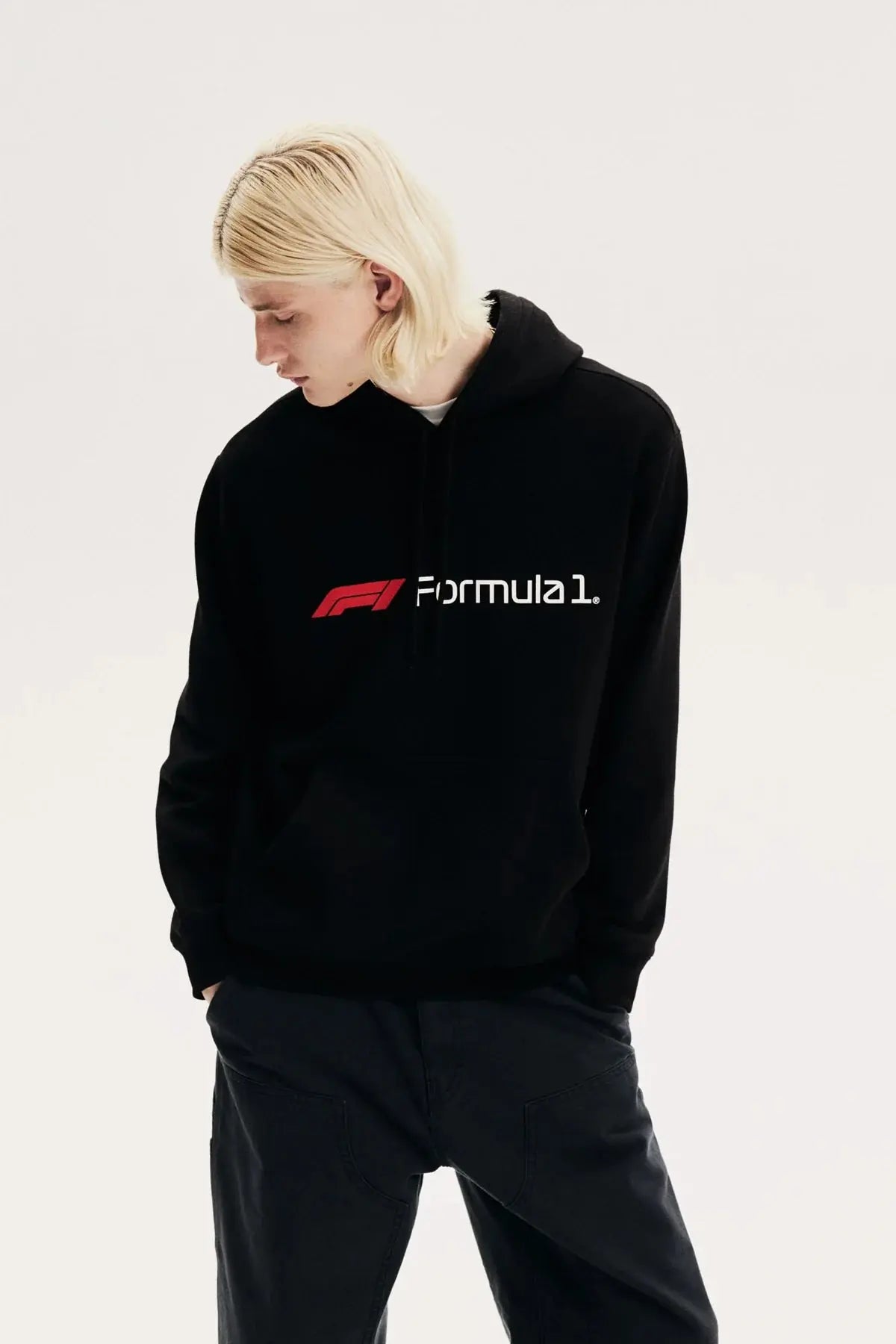 Blonde model wearing a black Formula 1 racing hoodie with red and white logo, casual streetwear