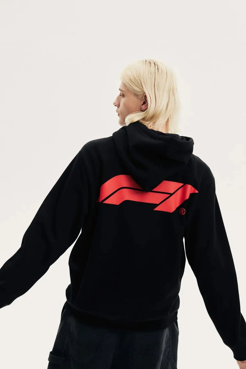 Back view of a person wearing a black fleece hoodie with a bold red racing graphic design.